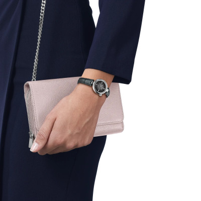 Une femme portant la Montre Tissot Desir Cadran Noir et Bracelet Cuir Noir