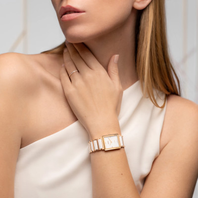 Une femme portant la montre Rado Integral Diamonds, cadran en nacre blanc, bracelet or rose, céramique blanche.