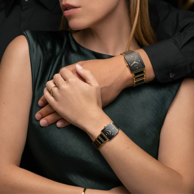 Une femme porte la montre Rado Integral Diamonds, cadran noir, bracelet bicolore noir et or.