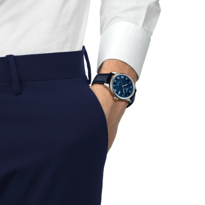 Un homme portant la montre Tissot Le Locle 39mm, cadran bleu, boîtier argent, bracelet cuir bleu.