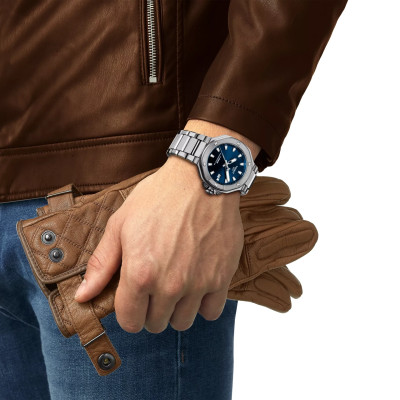Un homme portant la montre Tissot T-Race 41mm, cadran bleu, boîtier argent, bracelet métal argent.