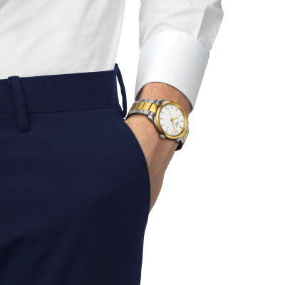 Un homme portant la montre Tissot PR 100 40mm, cadran blanc, bracelet bicolore doré.