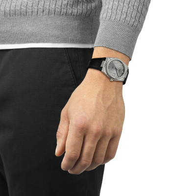 Un homme portant la montre Montre Tissot PRX Acier Damas 38 mm, Cadran Gris, Bracelet Cuir Noir Grainé