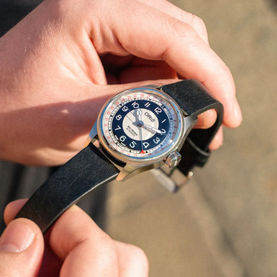 La montre Montre Oris Big Crown Pointer Date Bullseye tenue entre deux mains