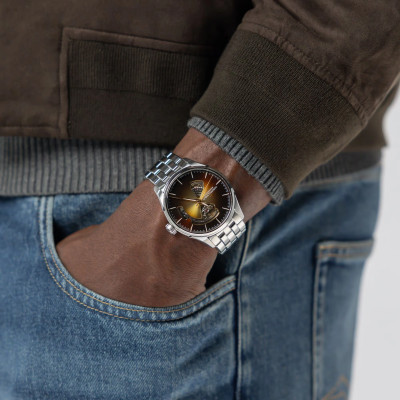 Photo avec les mains dans les poches, portant la Montre Jazzmaster Open Heart Auto 40 Mm Cadran Noir Bracelet Argenté